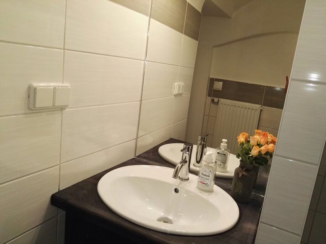 A bathroom with a white sink, a mirror, and a vase with flowers.