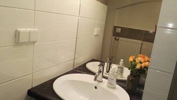 A bathroom with a white sink, a mirror, and a vase with flowers.
