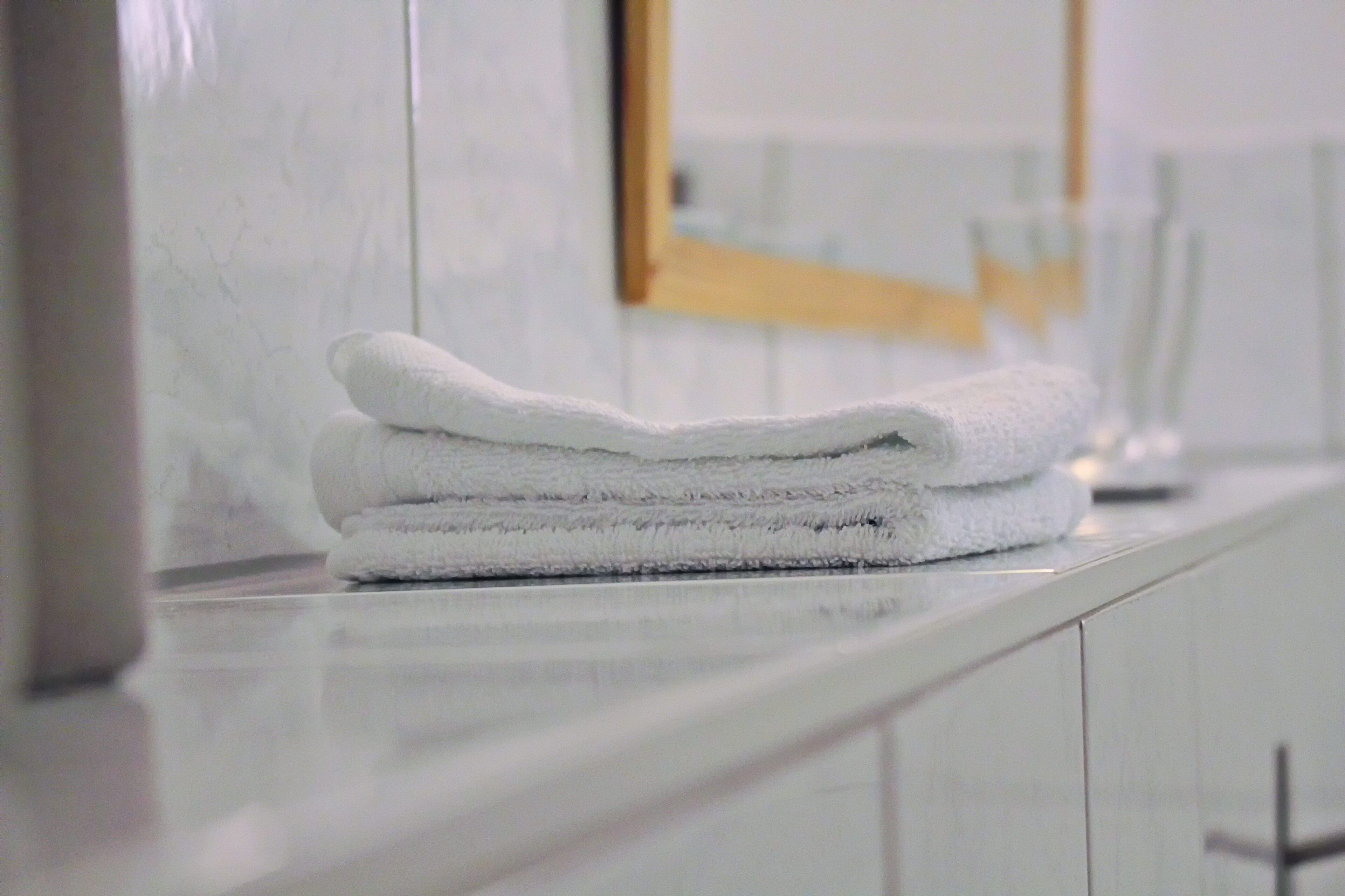 Un montón de toallas blancas sobre un mostrador de baño blanco.