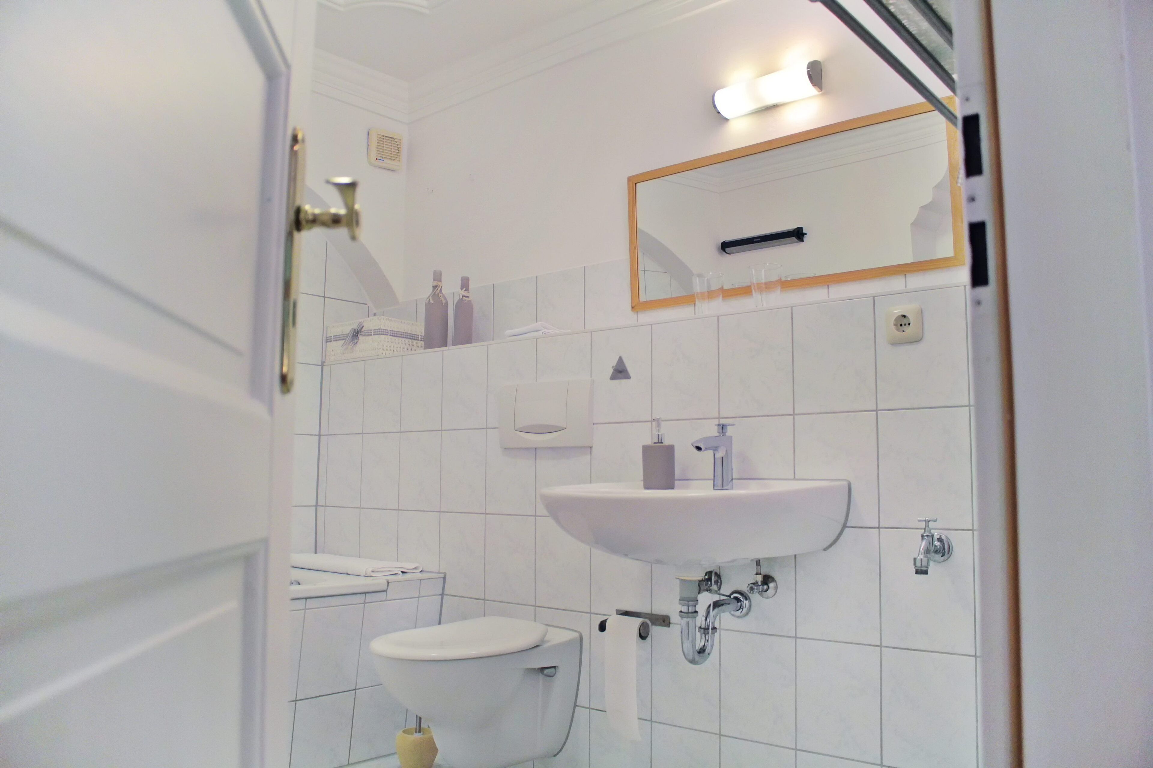 A bathroom with a toilet, sink, and mirror.