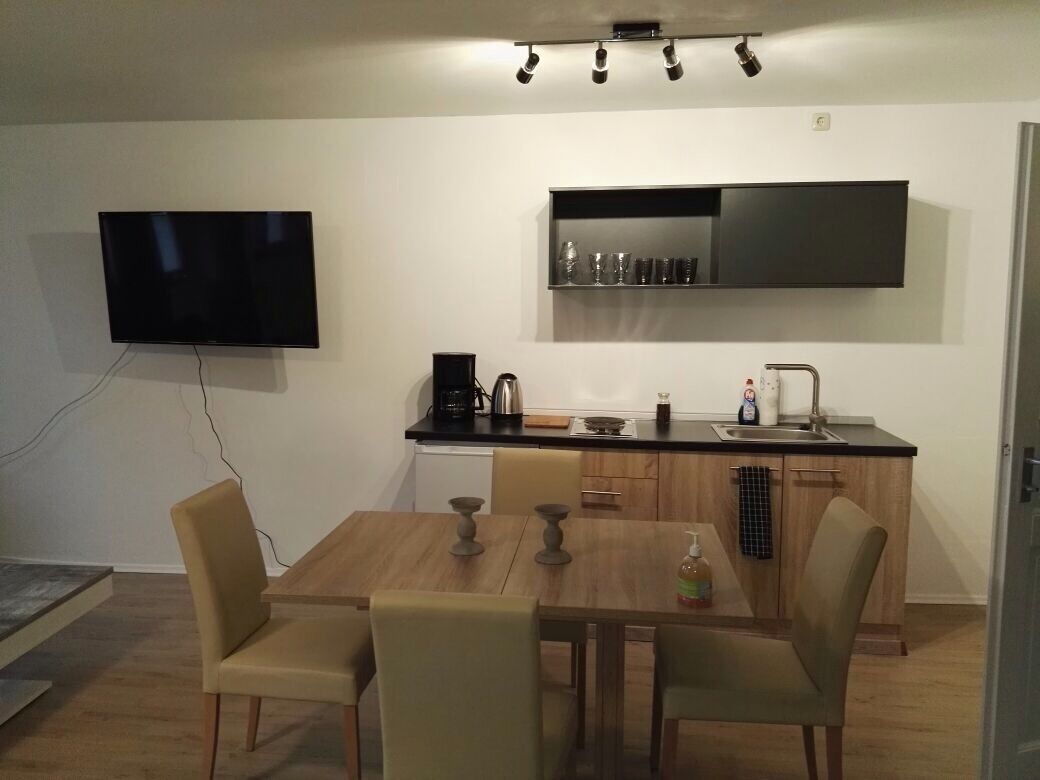 Una cocina moderna con televisor de pantalla plana, armarios de madera y un comedor con sillas.