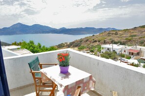 Un balcon avec une table, des chaises et un pot de fleurs.