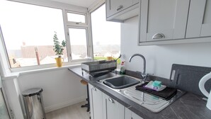 A modern kitchen with a sink, a trash bin, and a window with a view of buildings. - Old Shop (Newport)