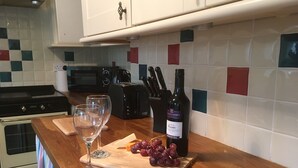 A kitchen counter with a cutting board, a bottle of wine, and two glasses. - Old Shop (Newport)