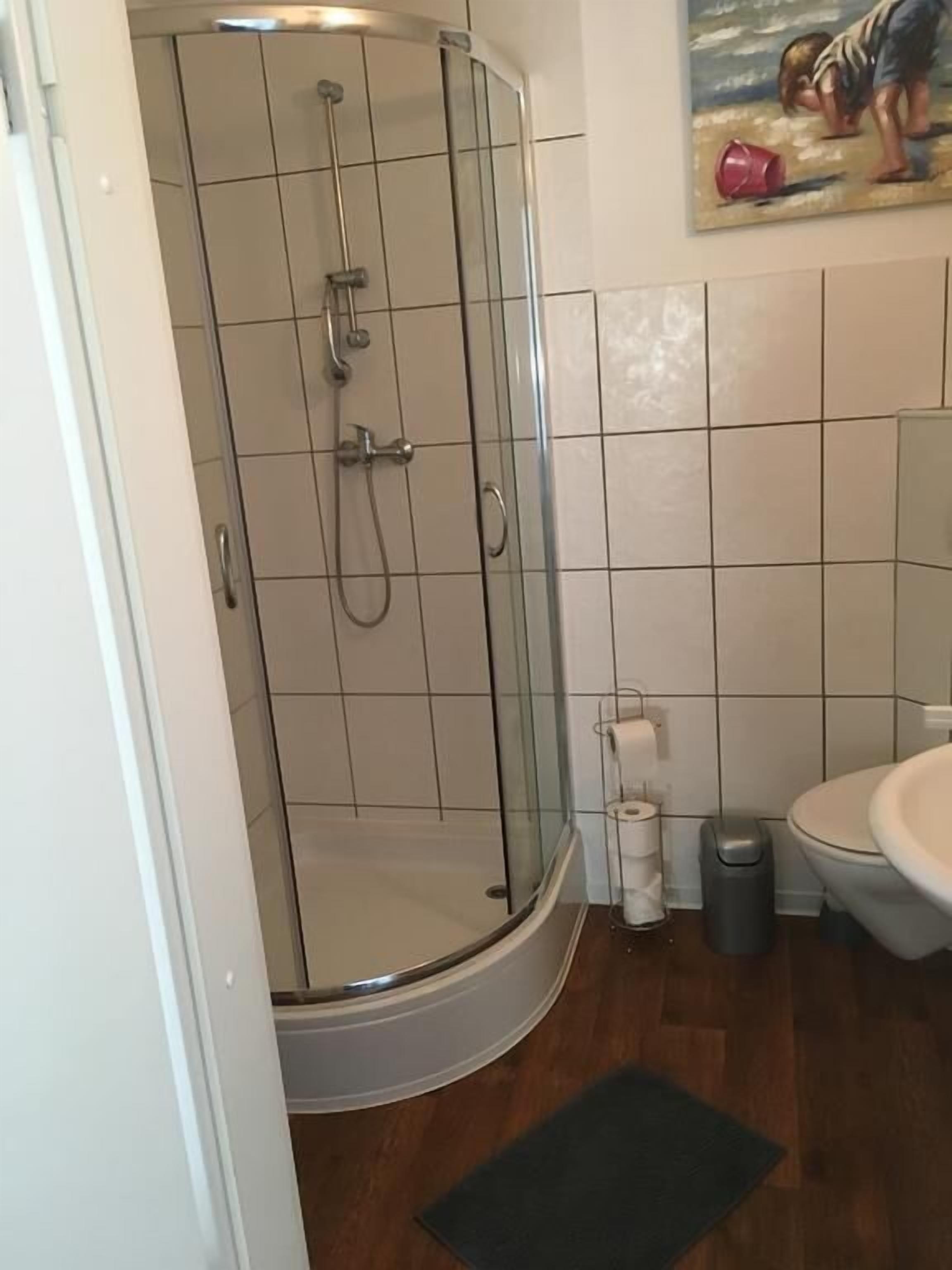 Een badkamer met een douchecabine van glas, een toilet en een wastafel.