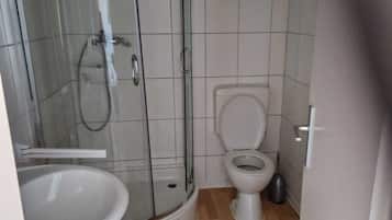 Ein Badezimmer mit Duschkabine aus Glas, Toilette und Waschbecken.