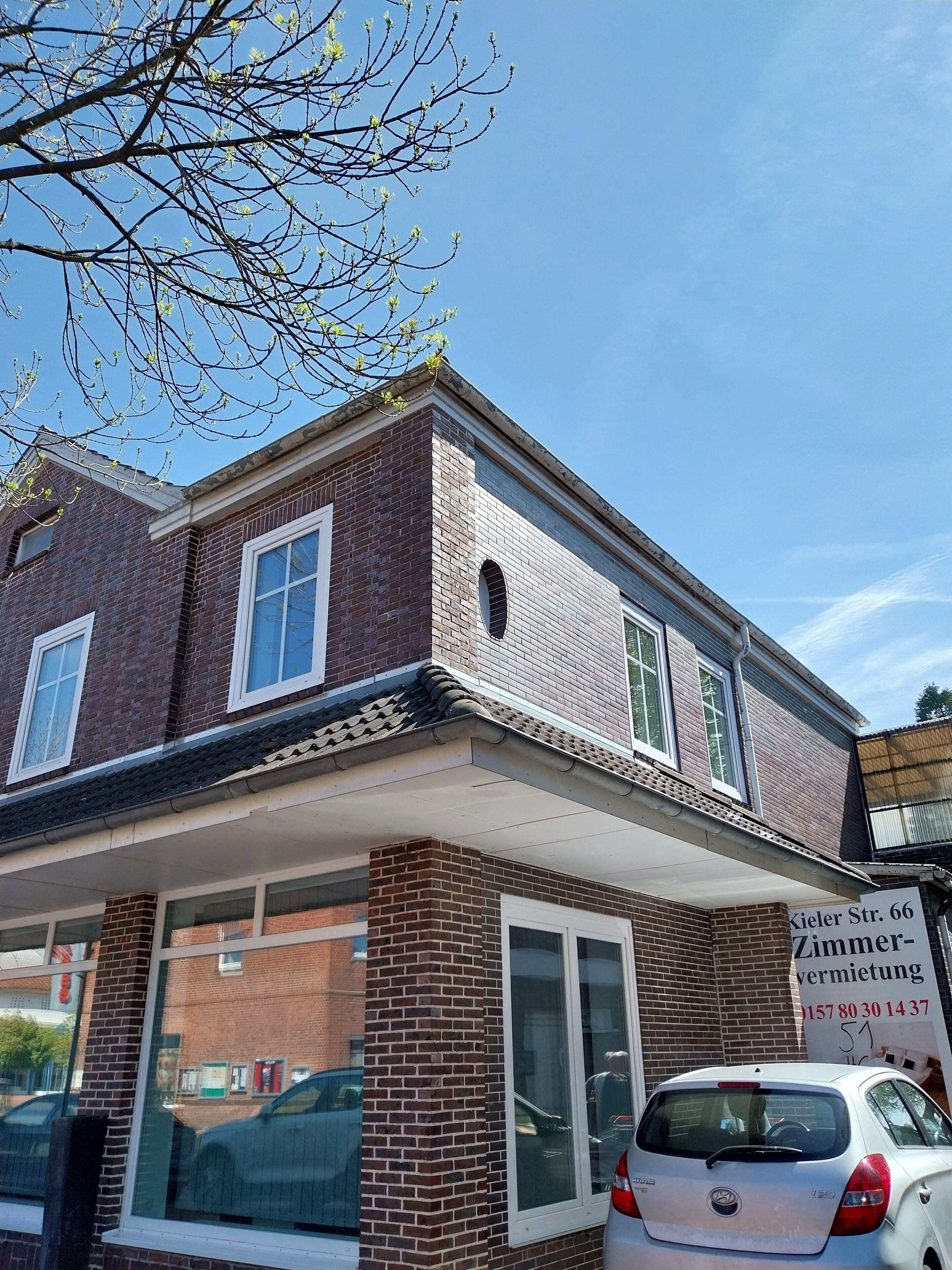 A two-story brick building with large windows and a visible sign indicating a business related to home improvement.