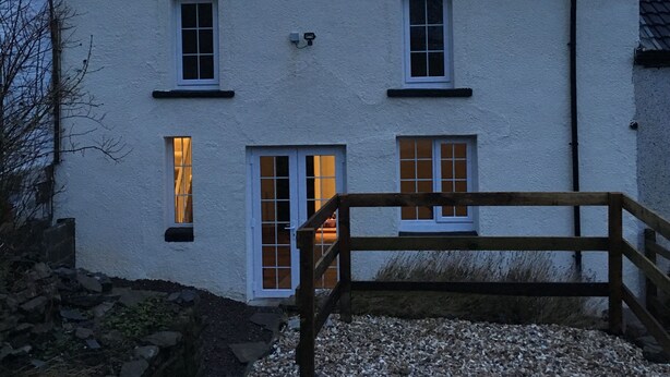 Un bâtiment blanc avec un toit en tuiles, une clôture en bois et une allée gravillonnée.