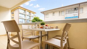 A balcony with a table set for breakfast, including a coffee pot, cups, and a fruit bowl. - Residence Columbia (San Michele al Tagliamento)