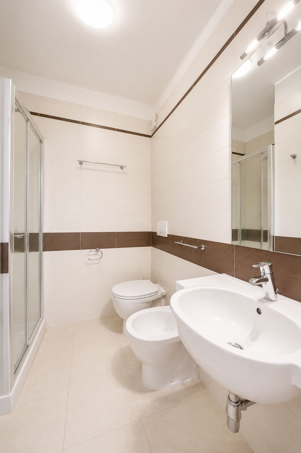 Un baño con cabina de ducha de vidrio, inodoro y lavabo con espejo.