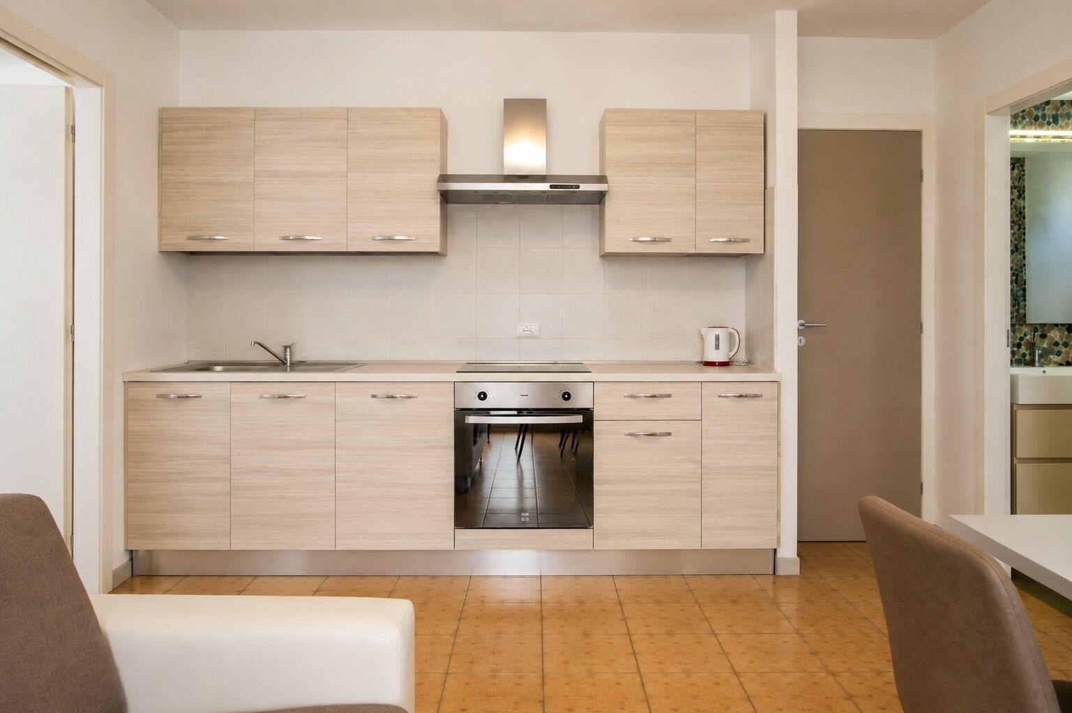 Eine moderne Küche mit hellen Holzschränken, einem Edelstahlherd und einem eingebauten Backofen.