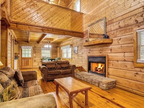 A log cabin interior with a fireplace, wooden furniture, and a dining area.