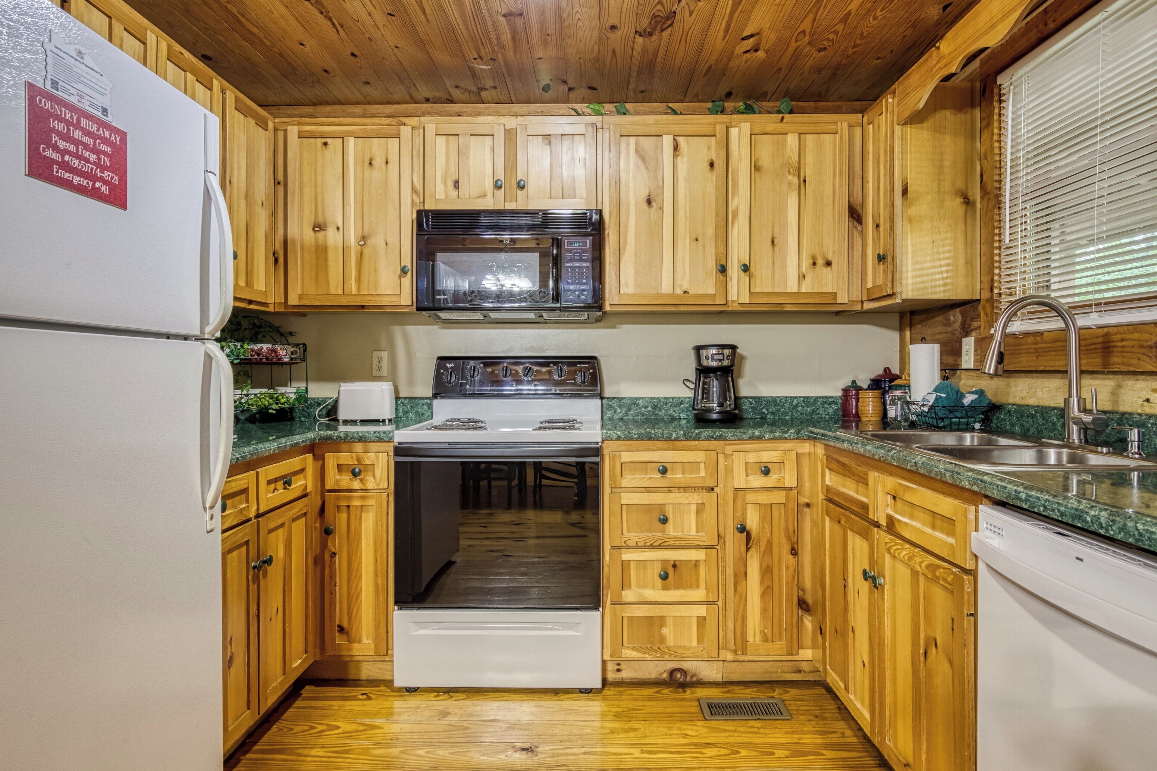 A kitchen with wooden cabinets, a white refrigerator, a stove, a microwave, and a sink.
