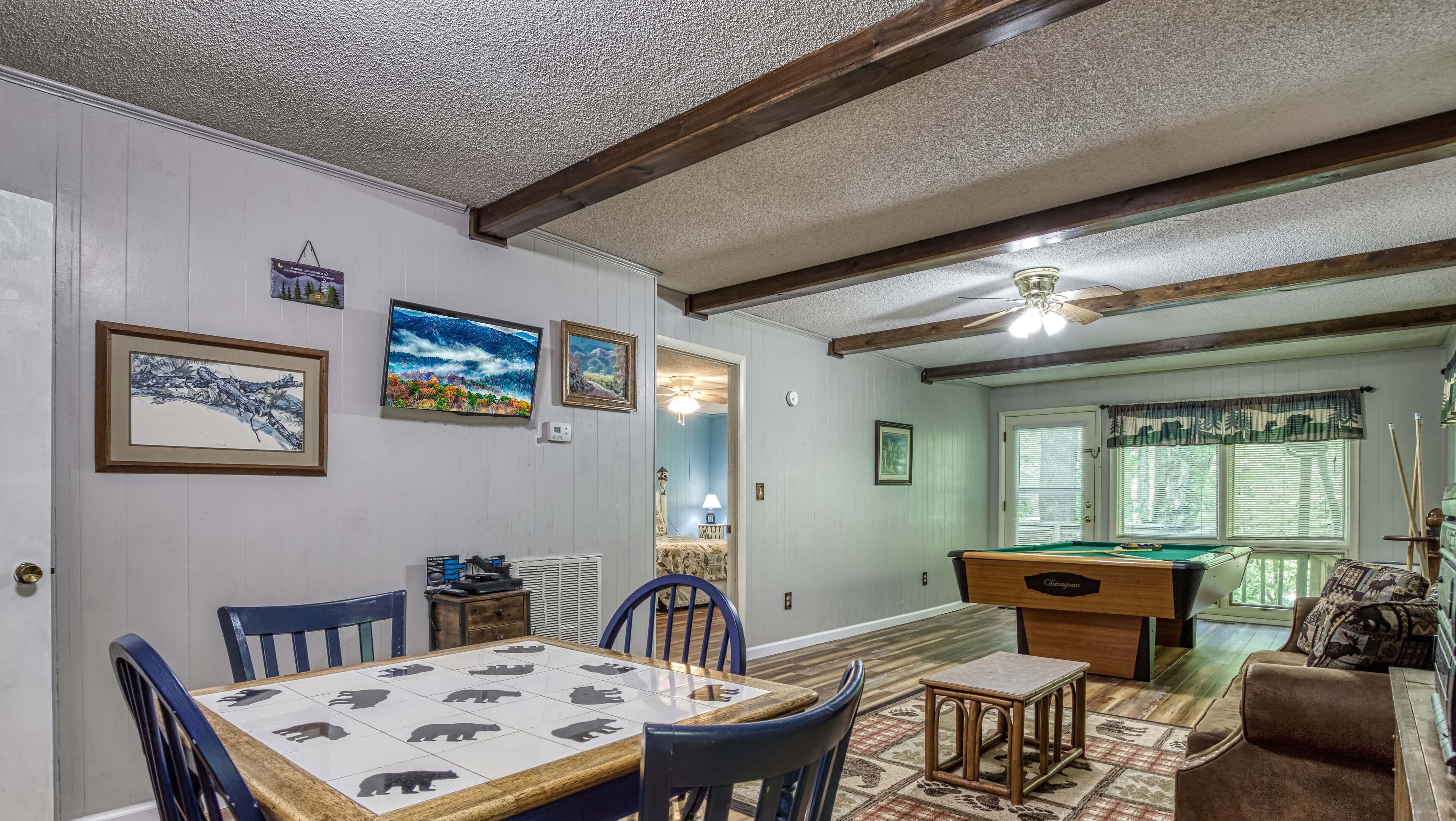 Un área de comedor con mesa de billar, sillas y una mesa decorada con motivos de oso.