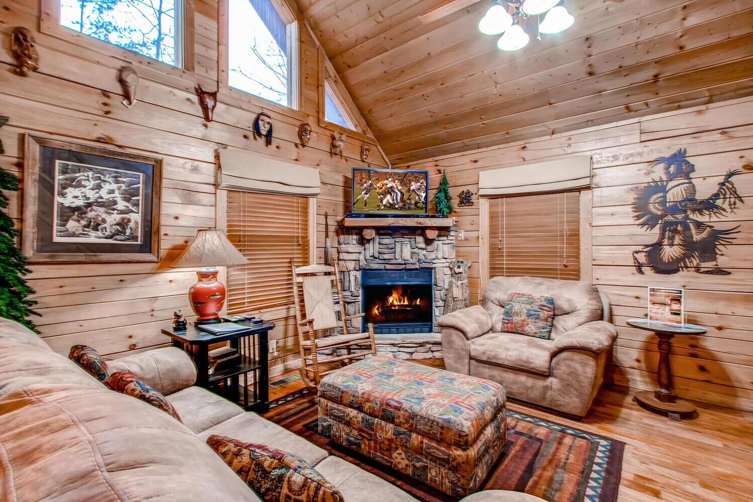 A cozy log cabin interior with a fireplace, plush furniture, and rustic decor.
