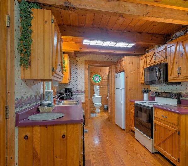 Une cuisine en bois équipée d’un réfrigérateur, d’une cuisinière et d’un four à micro-ondes.