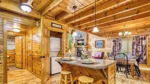 A wooden interior with a kitchen area, bar stools, and a dining table. - Sweet Dreams is a beautiful 2 bedroom and 2 bath log cabin (Sevierville)