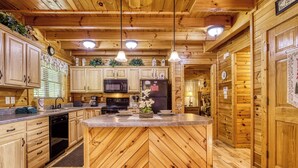 A wooden cabin-style kitchen with a herringbone floor pattern, wooden cabinets, a central island, and pendant lighting. - Sweet Dreams is a beautiful 2 bedroom and 2 bath log cabin (Sevierville)