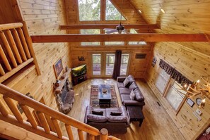 A cabin interior with a wooden floor, a sofa, a fireplace, and a dining table. - Amazing Views - The name says it all! (Sevierville)