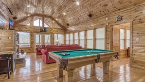 A wooden interior with a pool table, red sofa, and a fireplace. - Above The Clouds is a perfect Smoky Mountain Getaway for the family or 2 couples! (Sevierville)