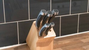 Um bloco de madeira para facas com várias facas sobre uma bancada de cozinha.