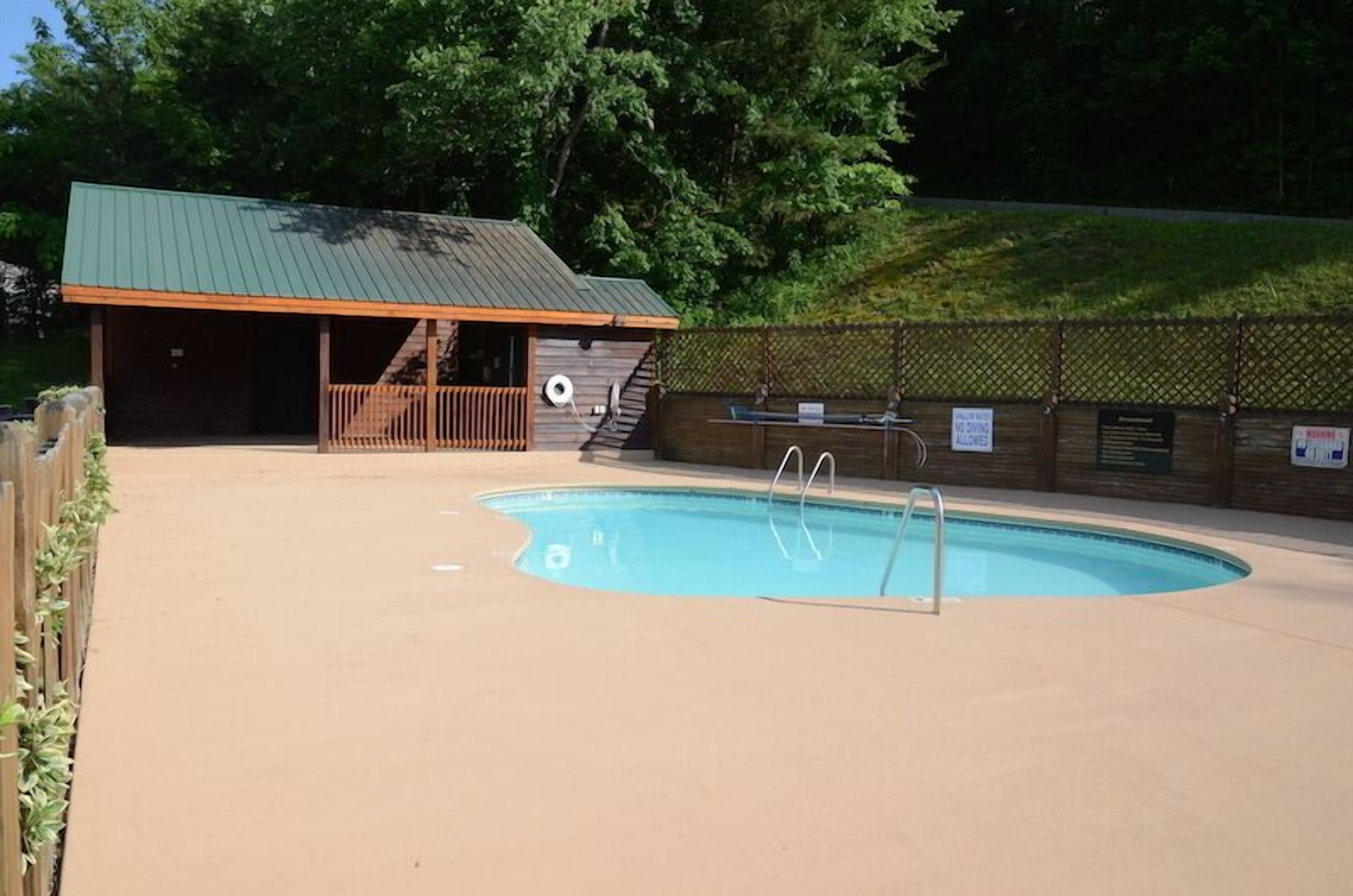 A swimming pool with a wooden deck and a covered area with a green roof.