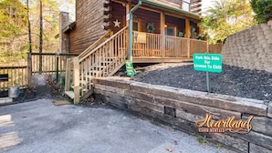 A wooden cabin with a porch and stairs leading up to the entrance. There is a sign indicating the parking area for license to chill.