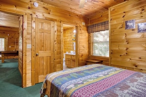 Ein Zimmer in einer Holzhütte mit einem Bett, einem Badezimmer und einem Essbereich.