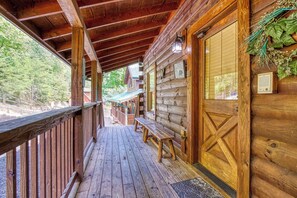 A wooden cabin with a covered porch, benches, and a door with a decorative panel.