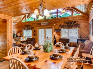 Cozy cabin interior with a dining area for four, a seating area, and a warm ambiance.