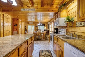 A cabin interior with a kitchen, dining area, and a sign reading 'Life - Love - Laughter'.