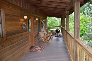 A wooden cabin with a porch, rocking chairs, and a barbecue grill. - Smokey Trails is the perfect romantic getaway for 2! (Sevierville)