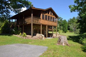 A two-story wooden cabin with a balcony, stone foundation, and a stone fireplace. - Smokey Trails is the perfect romantic getaway for 2! (Sevierville)