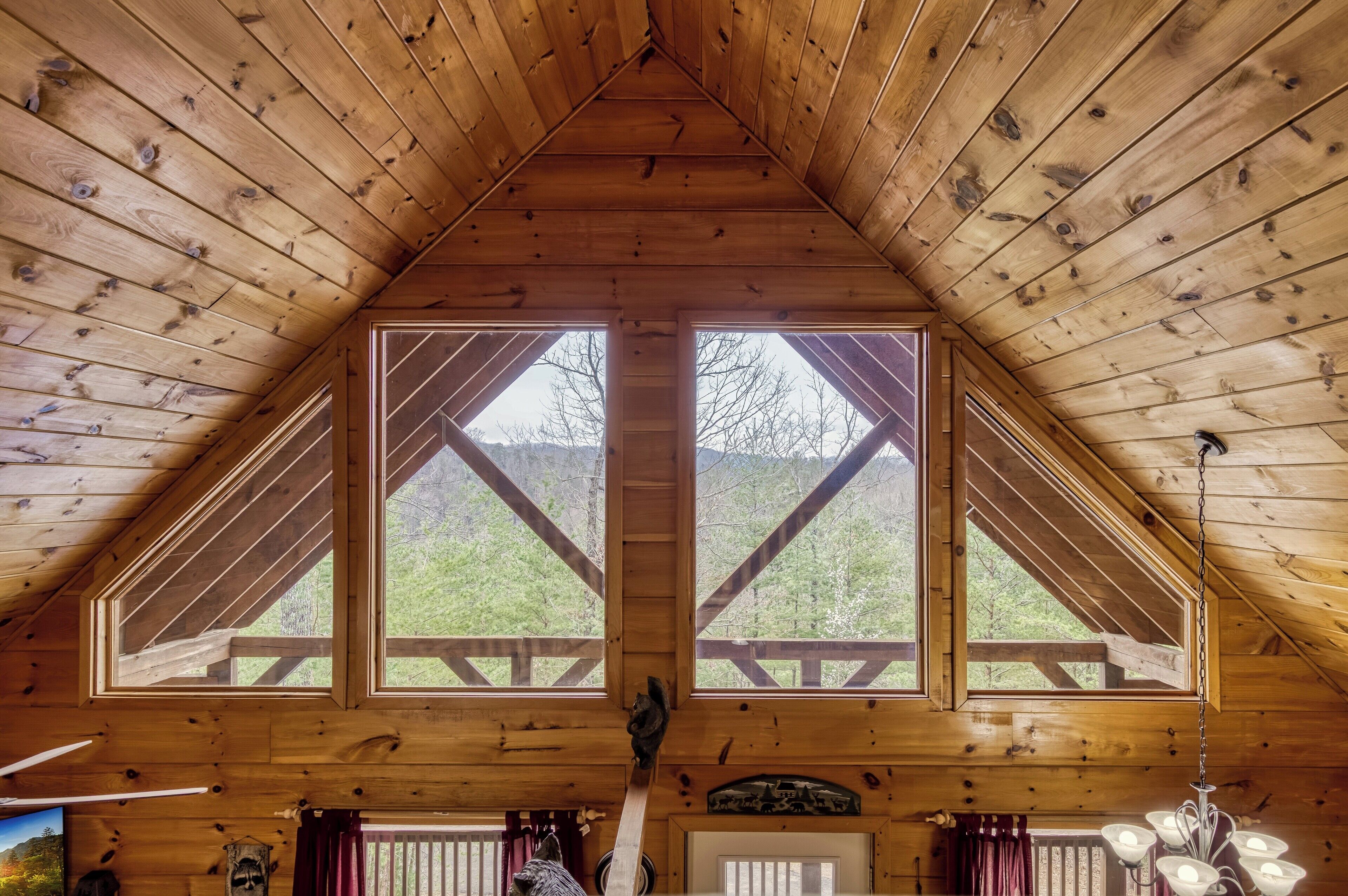Un interior de madera con techo inclinado, ventanas grandes y una escalera de madera.