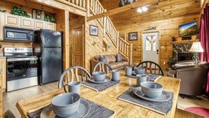 Interior de una cabaña de madera con comedor, cocina y sala de estar.