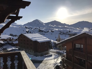 A snow-covered mountain village with wooden buildings and a clear view of the sun.