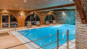 An indoor swimming pool with wooden walls, a stone accent wall, and a lifebuoy.