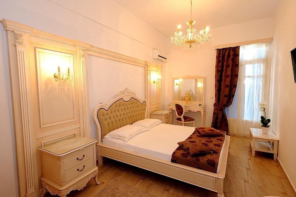 Une chambre à coucher avec un grand lit, des tables de chevet, une commode, un miroir et un lustre.