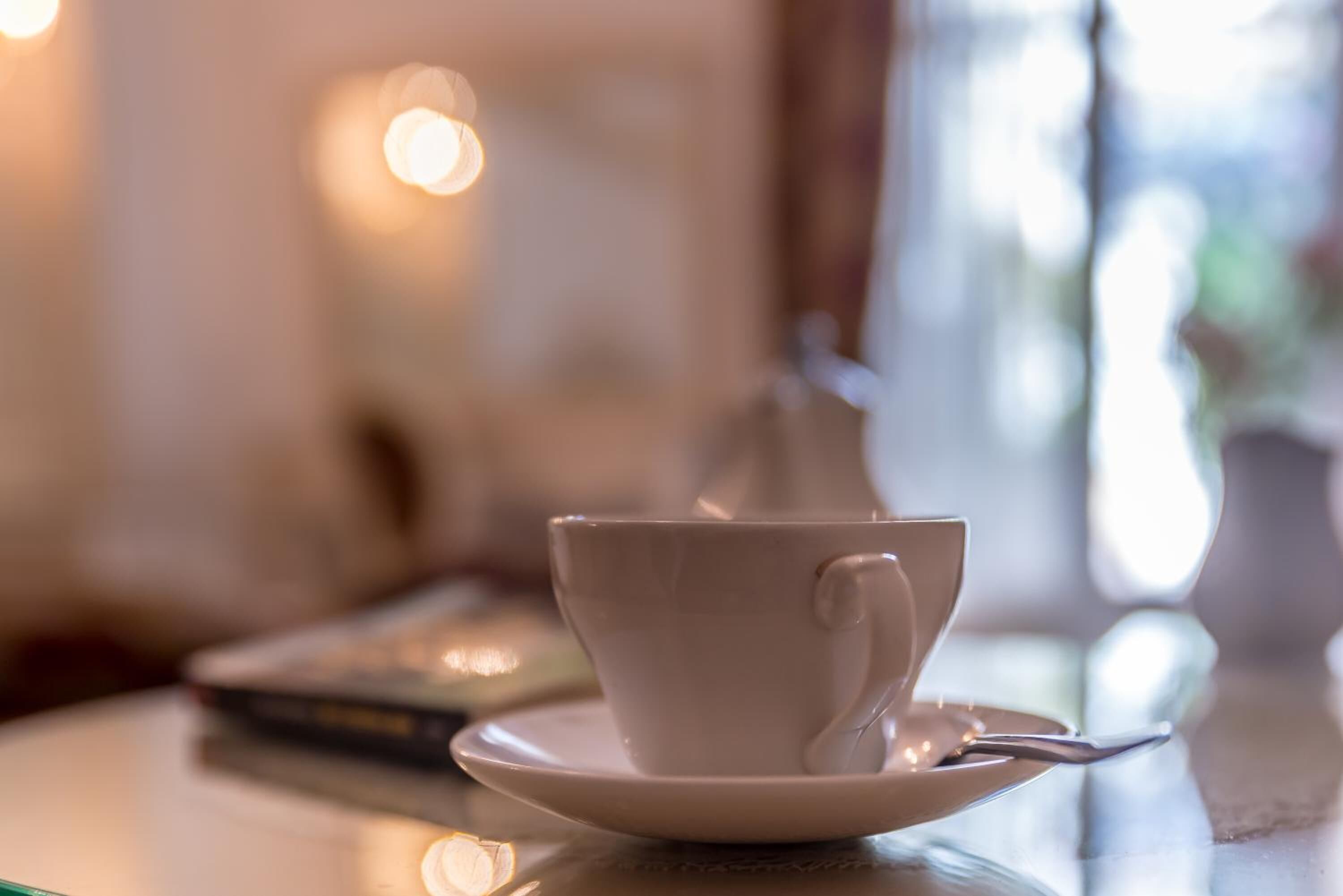 Una taza y platillo blancos sobre una mesa con fondo desenfocado.