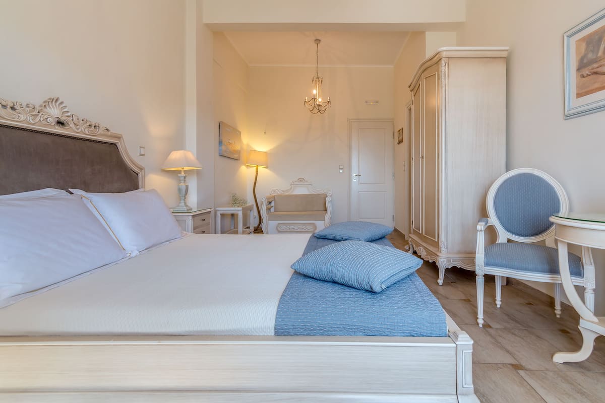 A neatly arranged bedroom with a bed, bedside tables, a chair, and a wardrobe.