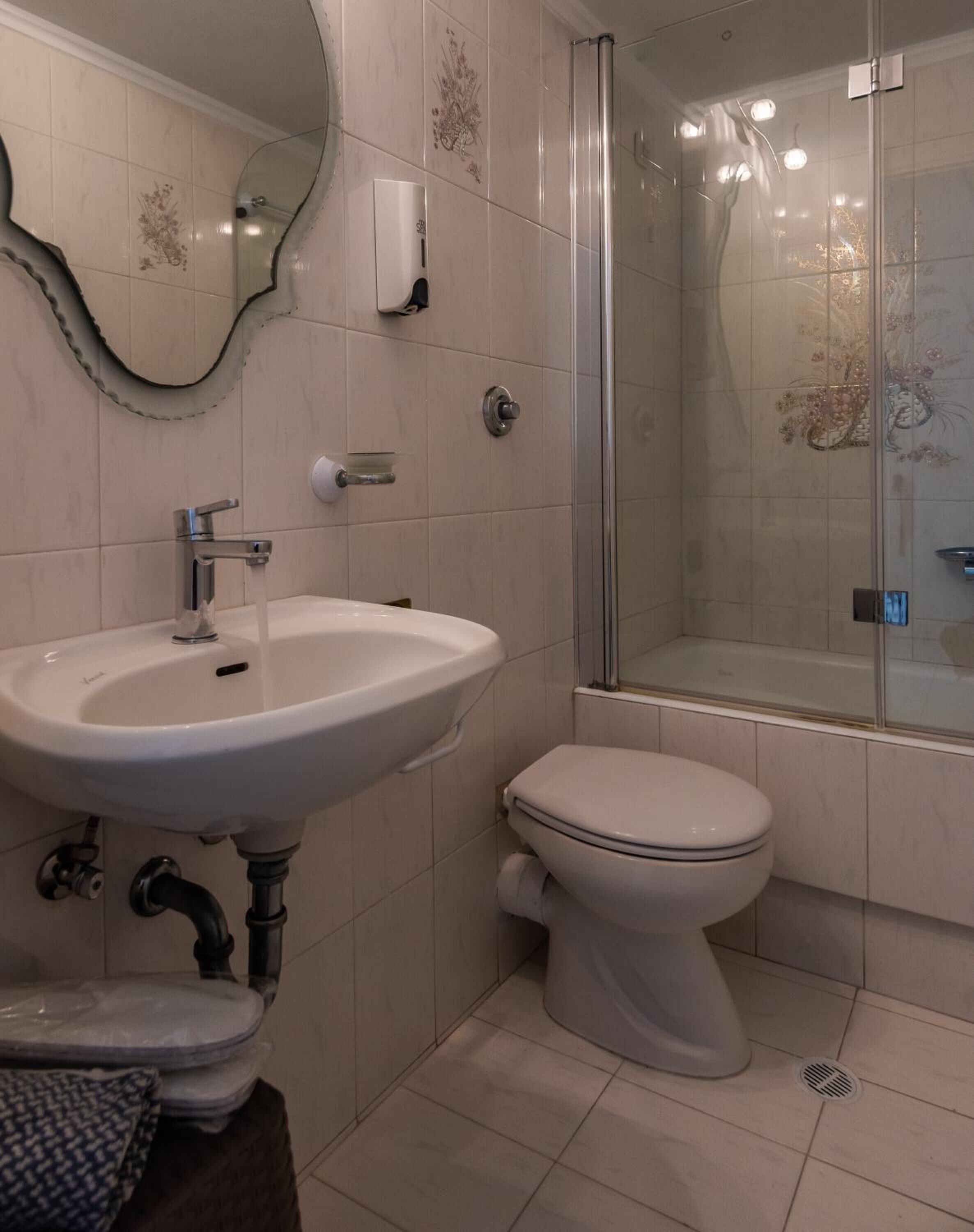 Une salle de bain avec un lavabo blanc, des toilettes et une douche à parois de verre.
