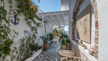Un espace extérieur étroit et abrité, doté d’un sol en pierre, de plantes en pot et d’un mur blanc orné d’une ancre.