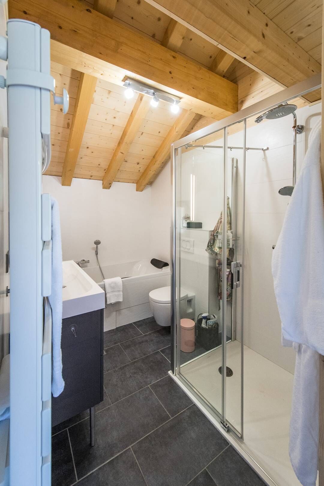 A modern bathroom with a glass shower enclosure, a white sink, and a bathtub.