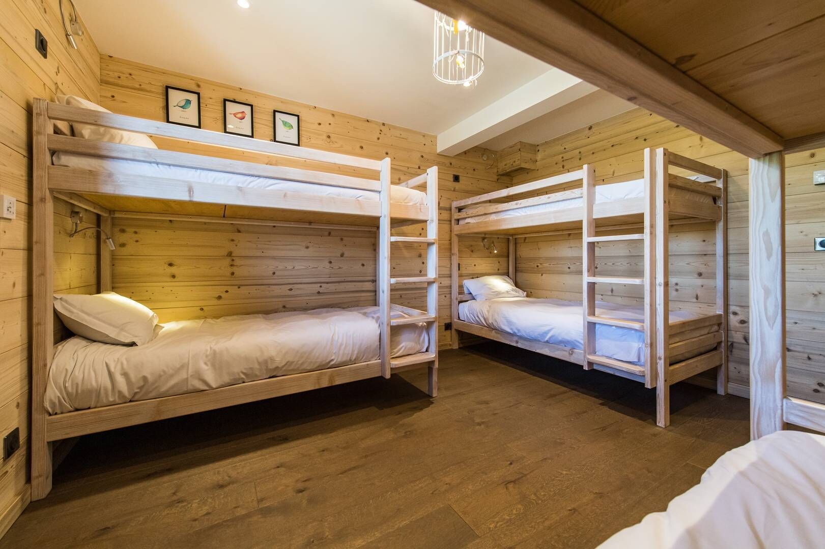 Una stanza con letti a castello, pareti e pavimento in legno, e una lampada a soffitto.