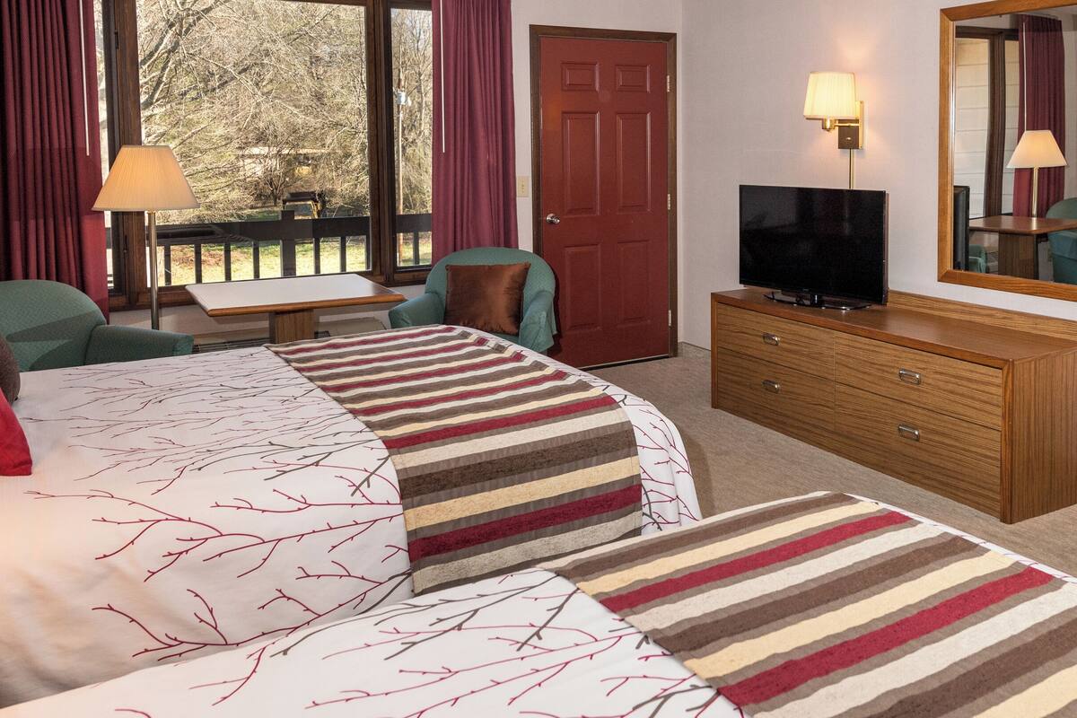 Una habitación de hotel con cama, televisor, escritorio y silla.