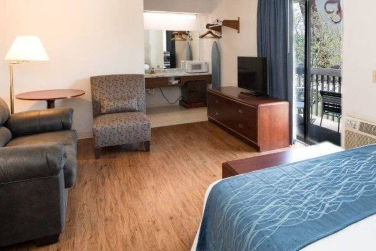 Una habitación de hotel con sofá, sillón, escritorio, televisión y cama.