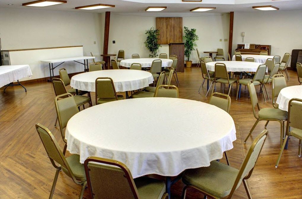 Un salón de conferencias con varias mesas redondas, cada una rodeada de sillas.
