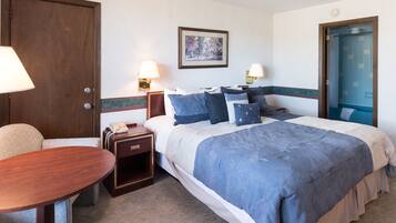 A hotel room with a bed, bedside lamps, a desk, and a chair.