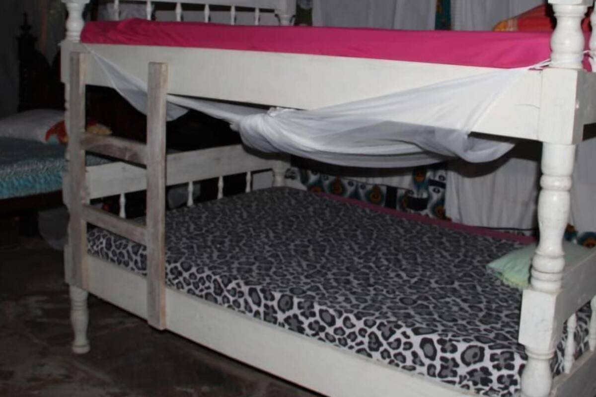 Un lit superposé avec une barre supérieure rose et un matelas à motifs léopard.