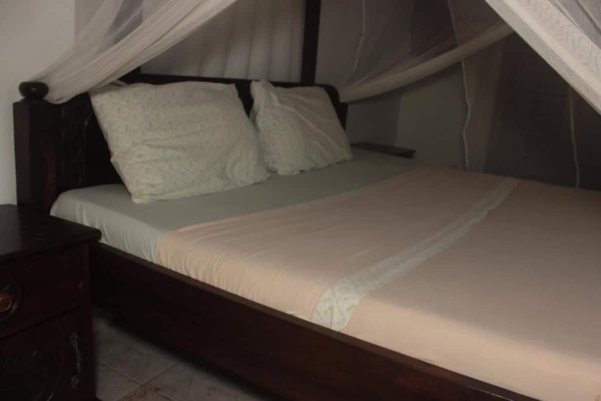 Un lit à baldaquin, avec une tête de lit en bois et une table de chevet.